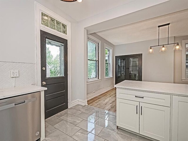 kitchen featuring decorative light fixtures, stainless steel dishwasher, a healthy amount of sunlight, and light tile patterned floors