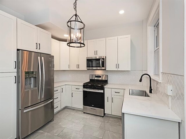 kitchen featuring appliances with stainless steel finishes, tasteful backsplash, sink, pendant lighting, and light tile patterned floors