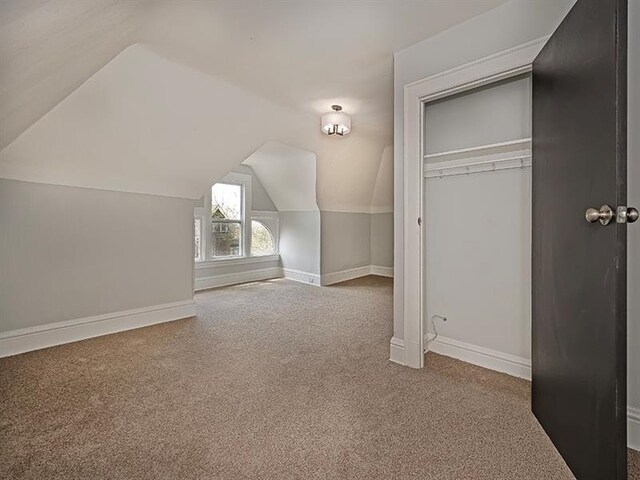 additional living space featuring lofted ceiling and carpet