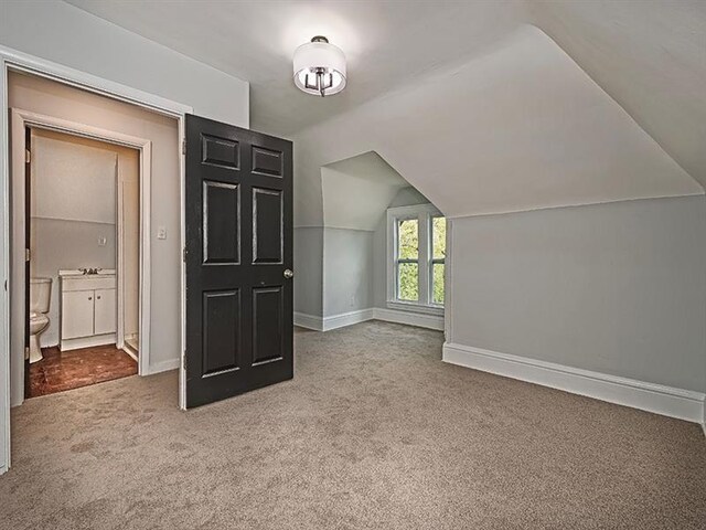 bonus room with carpet flooring and vaulted ceiling