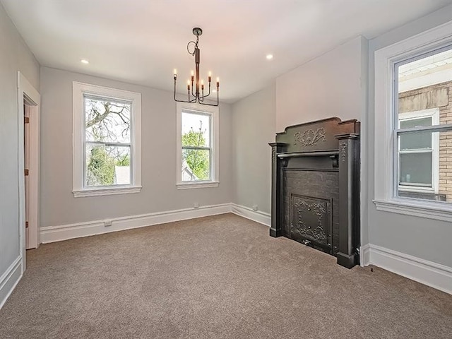 unfurnished living room with an inviting chandelier, a fireplace, and carpet flooring