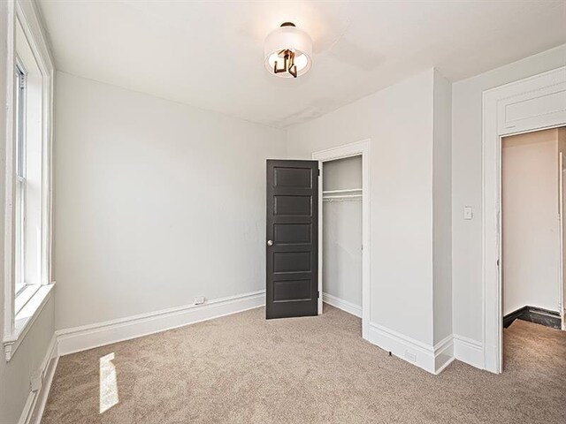 unfurnished bedroom featuring light carpet and a closet