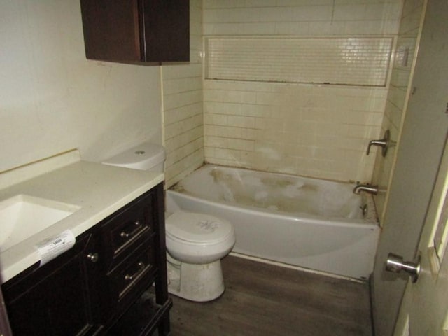 full bathroom with hardwood / wood-style flooring, tiled shower / bath, vanity, and toilet