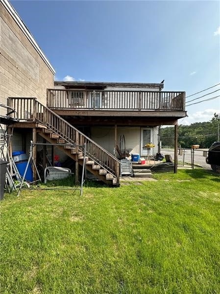 rear view of house with a wooden deck and a lawn