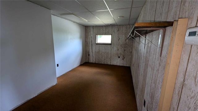 basement with a paneled ceiling and carpet