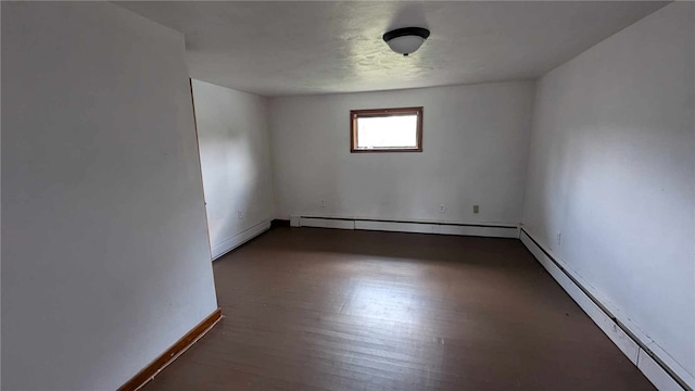 spare room with a baseboard heating unit and dark hardwood / wood-style floors