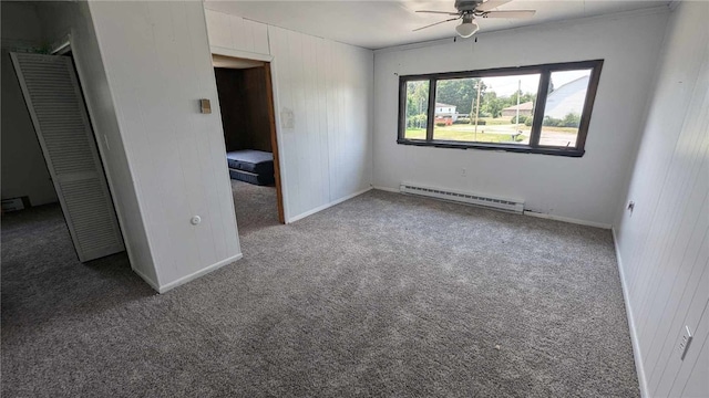 interior space featuring wooden walls, baseboard heating, ceiling fan, a closet, and carpet floors