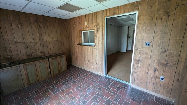 empty room with a paneled ceiling and wooden walls