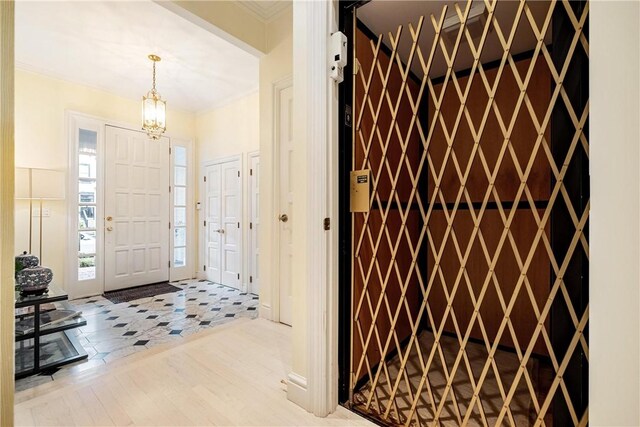 tiled foyer entrance featuring crown molding and an inviting chandelier