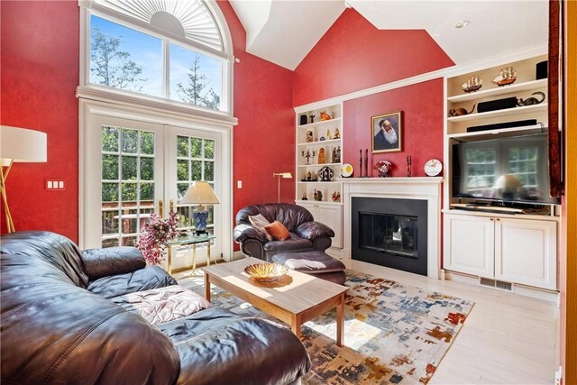 living room with high vaulted ceiling, french doors, built in shelves, and light hardwood / wood-style floors