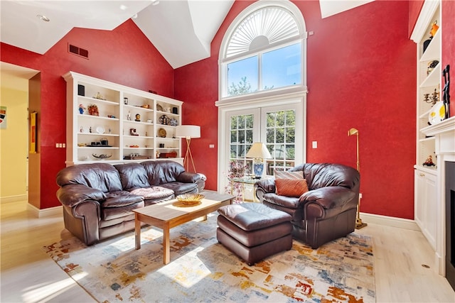 living room featuring high vaulted ceiling, french doors, and light hardwood / wood-style floors