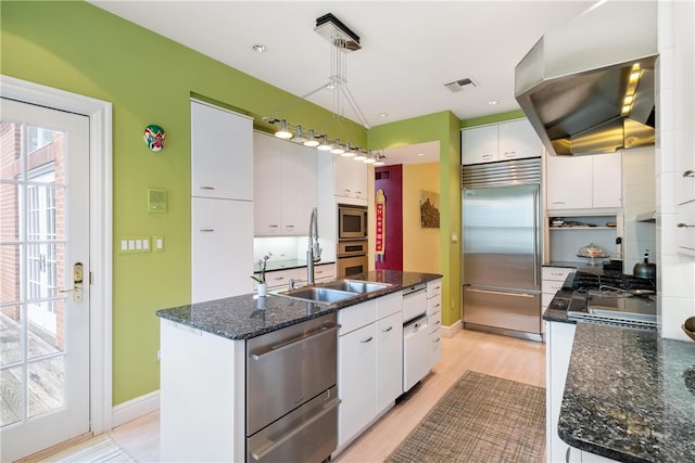 kitchen featuring built in appliances, decorative light fixtures, light hardwood / wood-style flooring, and white cabinets