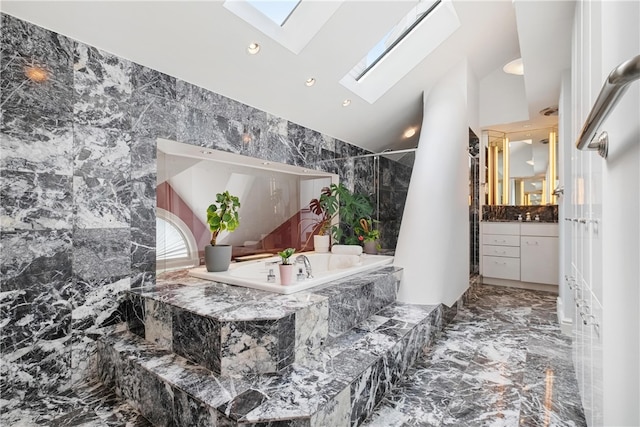 bathroom with vanity, tiled bath, tile walls, a skylight, and tile patterned flooring