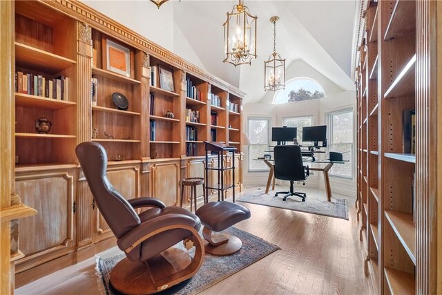 office area featuring light hardwood / wood-style flooring, a chandelier, and high vaulted ceiling