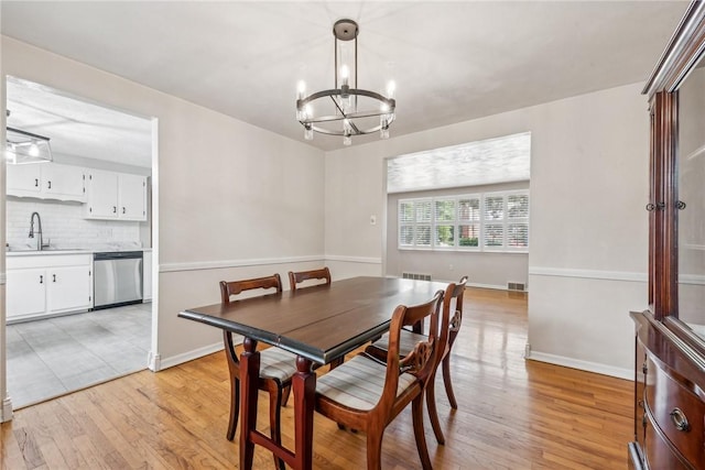 dining area featuring sink, light hardwood / wood-style flooring, and a chandelier