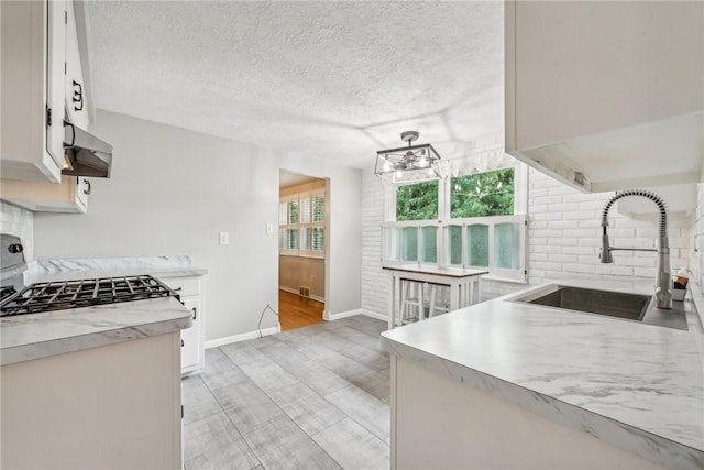 kitchen with extractor fan, tasteful backsplash, white cabinetry, sink, and light hardwood / wood-style flooring