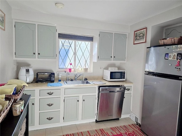 kitchen featuring appliances with stainless steel finishes, light tile patterned floors, white cabinets, and sink