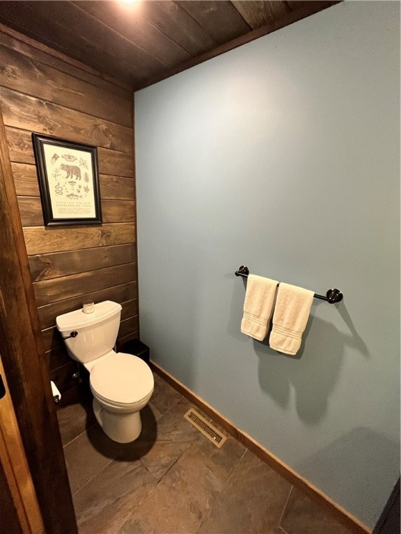 bathroom featuring tile patterned flooring, wood ceiling, toilet, and wooden walls