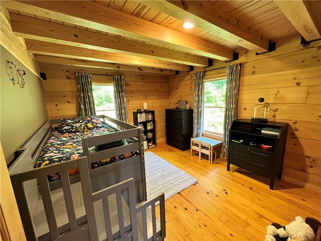 playroom with beamed ceiling, a wealth of natural light, wooden walls, and light hardwood / wood-style floors