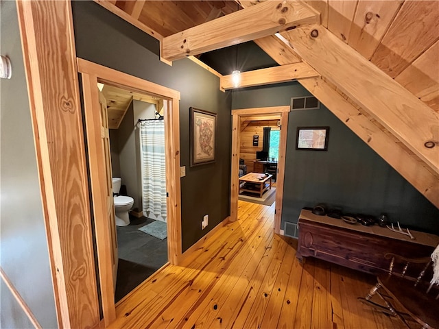 hallway featuring lofted ceiling with beams, plenty of natural light, and light hardwood / wood-style floors