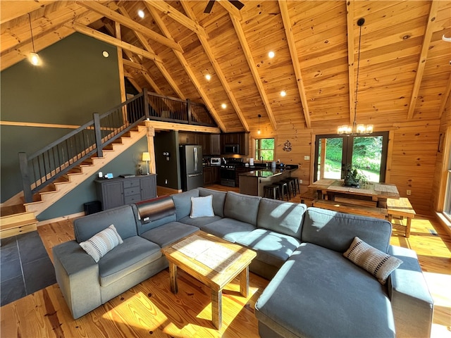 living room with a notable chandelier, lofted ceiling with beams, wooden walls, and wooden ceiling