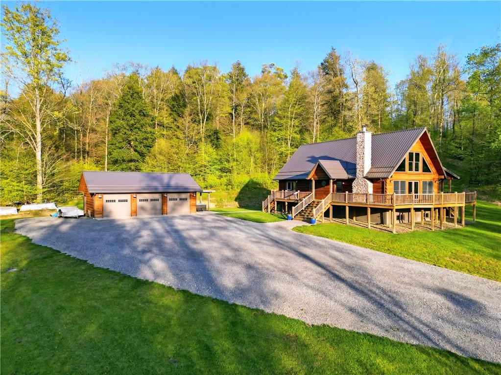 500 Seneca Hemlock Rd, Rockland Twp, PA 16374 - log-style house featuring a detached garage, a wooded view, a chimney, a deck, and an outbuilding