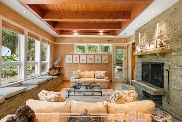 living room featuring a stone fireplace, light hardwood / wood-style flooring, and a healthy amount of sunlight