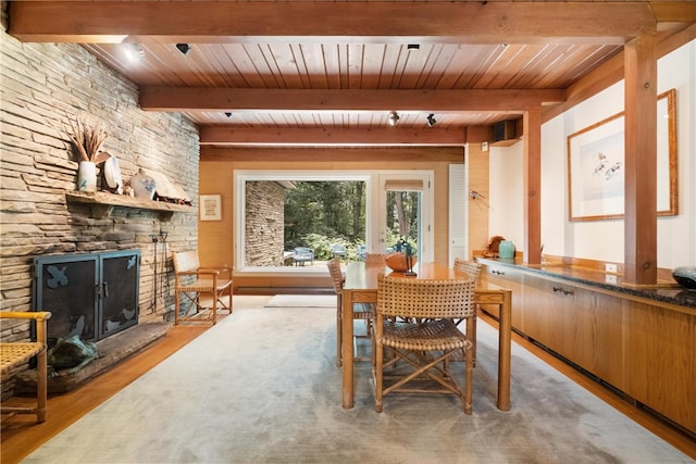 dining room featuring beam ceiling, a fireplace, light hardwood / wood-style floors, and wooden ceiling