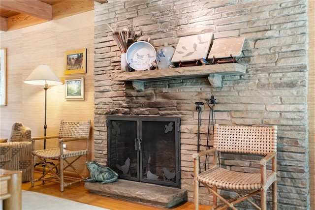 interior details with beam ceiling, hardwood / wood-style flooring, and a stone fireplace