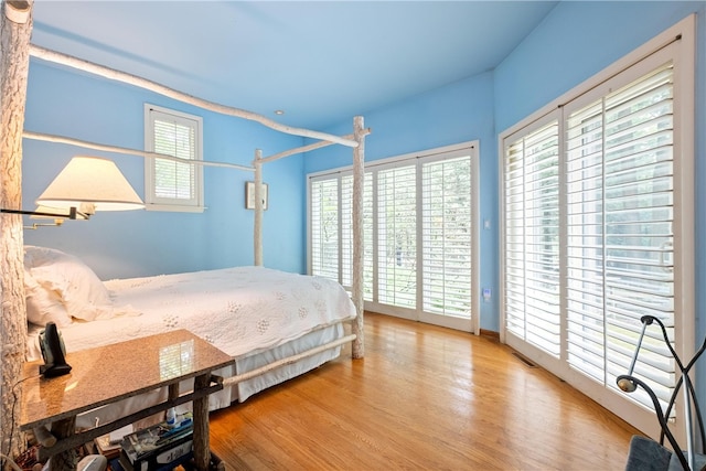 bedroom with access to exterior and wood-type flooring