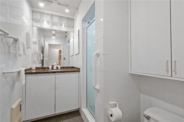 bathroom with tile walls, vanity, toilet, and walk in shower