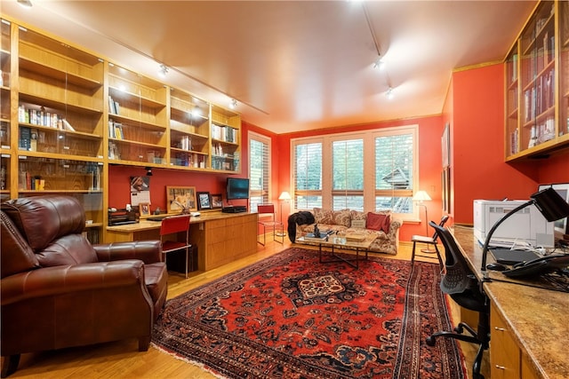 office featuring light hardwood / wood-style floors, built in desk, and track lighting