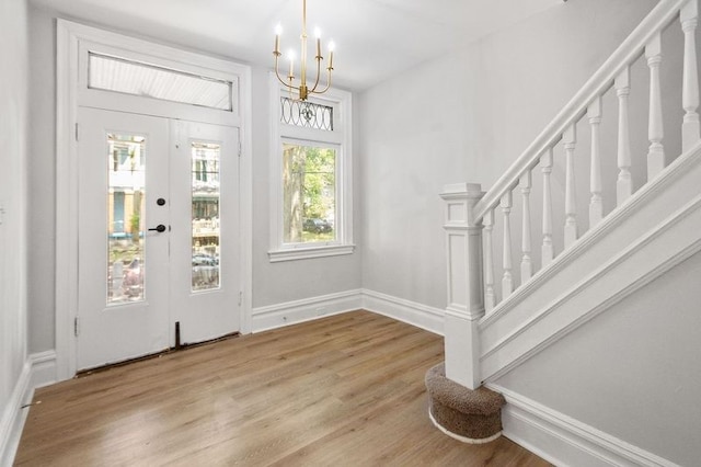 entrance foyer with light hardwood / wood-style floors, french doors, and a chandelier