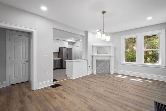 unfurnished living room with a stone fireplace and light hardwood / wood-style flooring