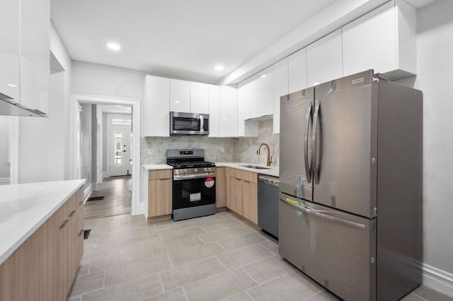 kitchen featuring white cabinetry, tasteful backsplash, stainless steel appliances, sink, and light hardwood / wood-style floors