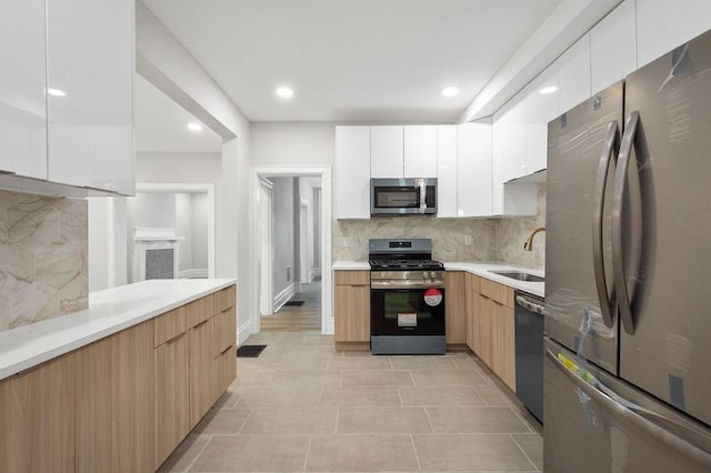 kitchen with white cabinetry, tasteful backsplash, stainless steel appliances, sink, and light tile patterned floors