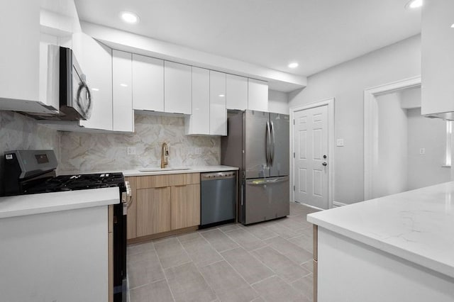 kitchen featuring sink, white cabinetry, backsplash, and stainless steel appliances