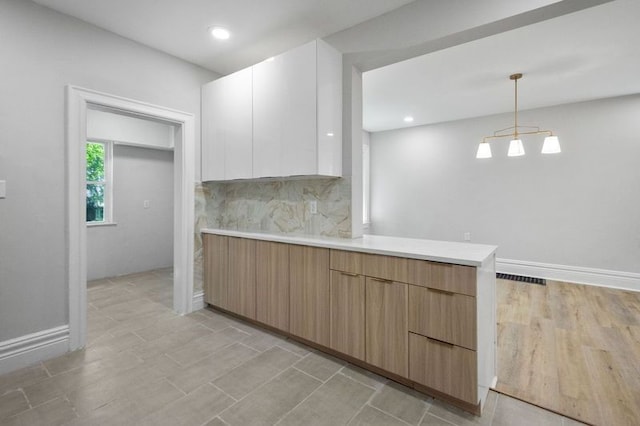 kitchen featuring decorative backsplash, white cabinetry, light hardwood / wood-style floors, and decorative light fixtures