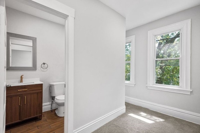 bathroom with a healthy amount of sunlight, vanity, hardwood / wood-style flooring, and toilet