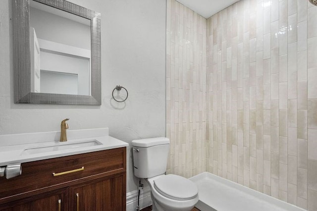 bathroom featuring tiled shower, vanity, and toilet