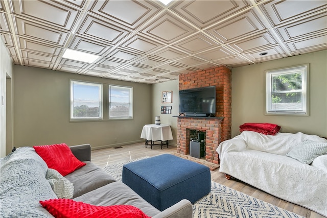 living room featuring a fireplace, light hardwood / wood-style flooring, and brick wall