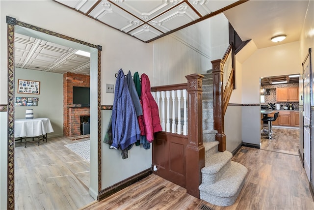 interior space featuring brick wall, a brick fireplace, coffered ceiling, and light wood-type flooring