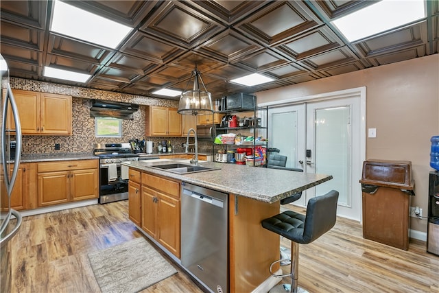 kitchen with range, light hardwood / wood-style flooring, stainless steel dishwasher, decorative backsplash, and a kitchen island with sink