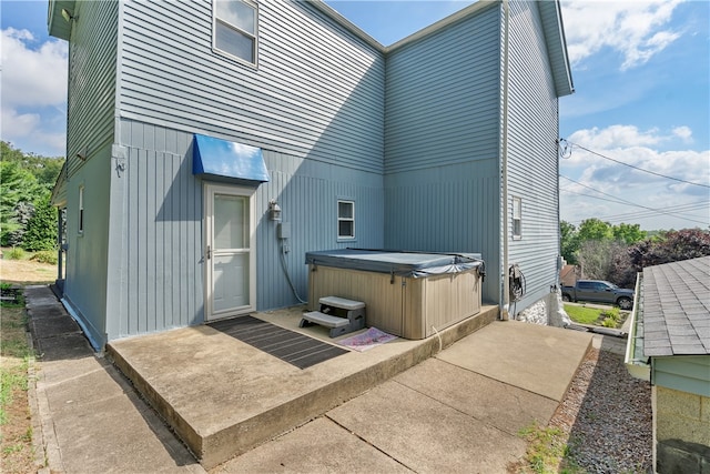 rear view of property featuring a patio and a hot tub