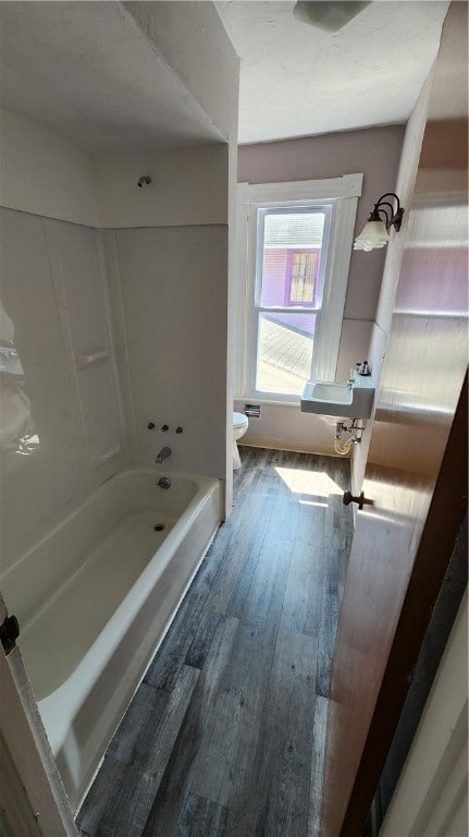 bathroom featuring wood-type flooring, toilet, and  shower combination