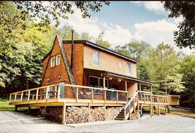 rear view of house with a wooden deck and faux log siding