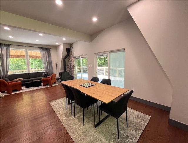 dining area featuring a wood stove, baseboards, dark wood-type flooring, and recessed lighting