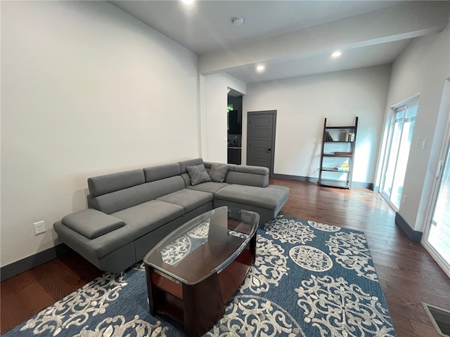 living area with baseboards, visible vents, wood finished floors, and beamed ceiling