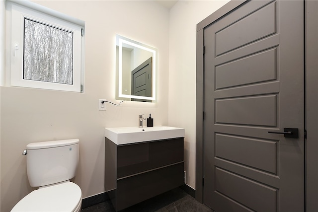 half bath featuring vanity, toilet, and baseboards