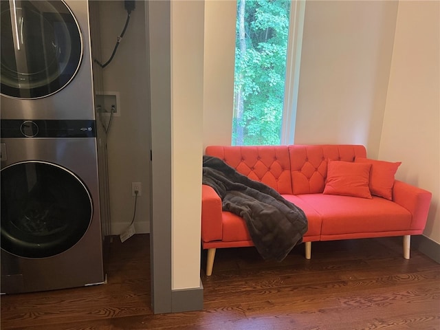 laundry area featuring wood finished floors, stacked washer and clothes dryer, baseboards, and laundry area